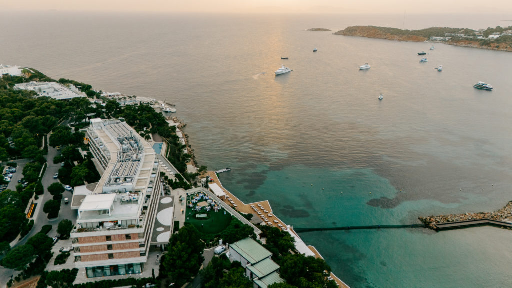 Drone view of a luxury seaside wedding venue in Greece showing dining area, dancing floor, and waterfront lounge deck.