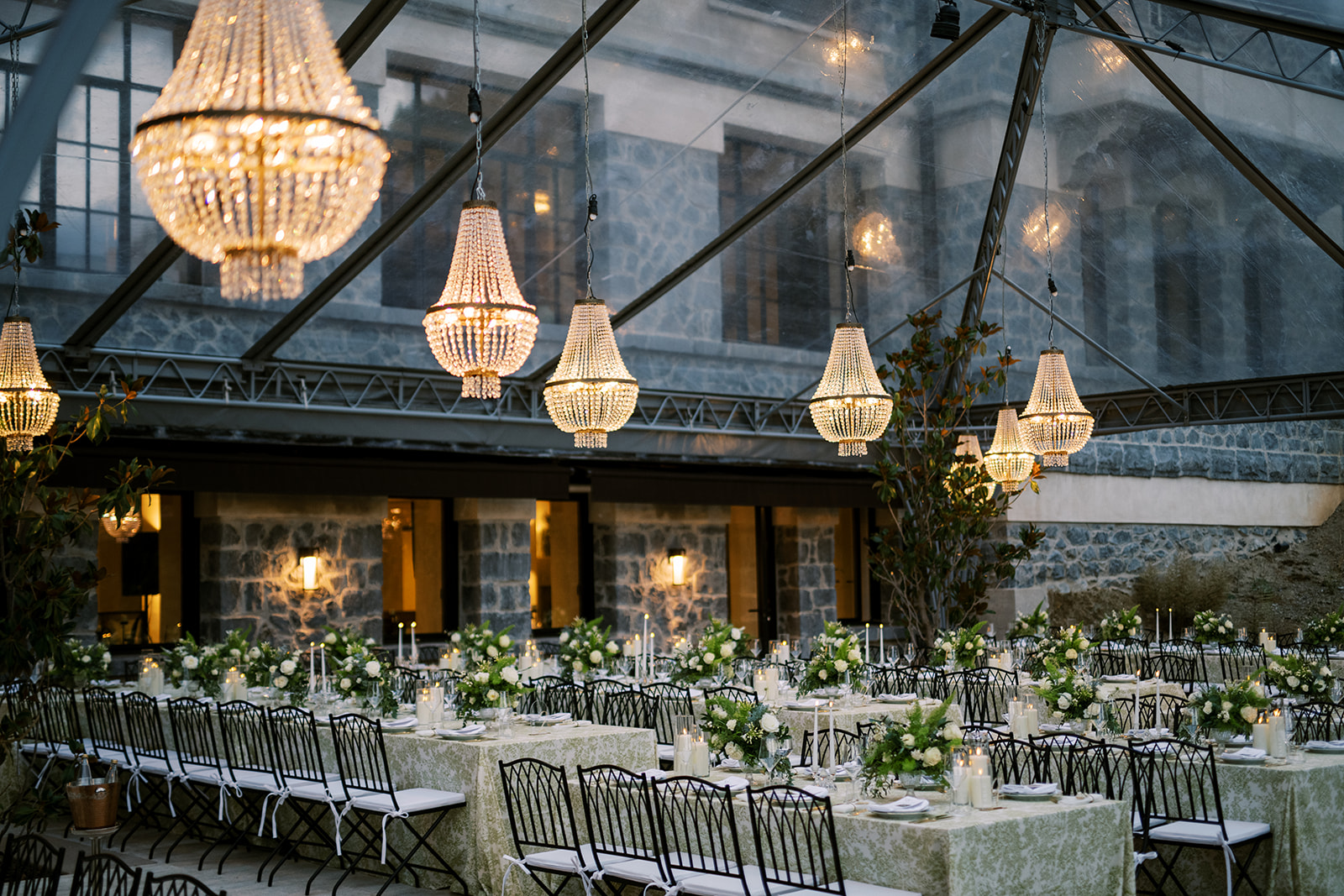 Lush floral arrangements with white roses and greenery decorating a traditional Greek Orthodox wedding ceremony table.