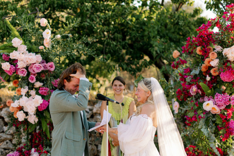 Smiling couple holding a bright pink and orange bouquet during their winery wedding in Crete