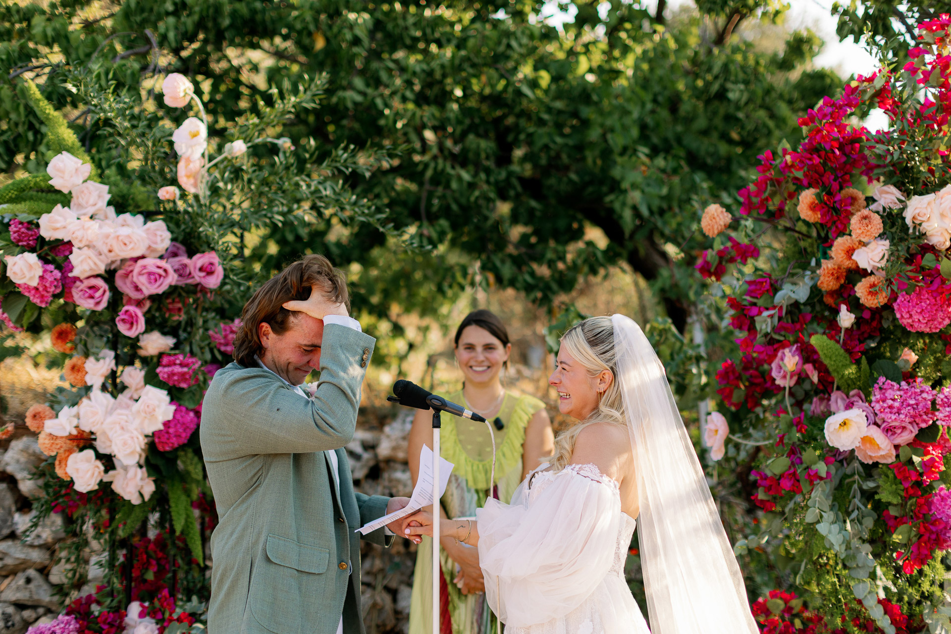 Smiling couple holding a bright pink and orange bouquet during their winery wedding in Crete